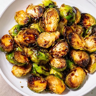 Freshly roasted Brussels Sprouts with Balsamic Glaze garnished with toasted nuts, perfect for an easy gluten-free dinner.