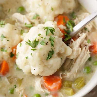 This hearty bowl of Slow Cooker Chicken and Dumplings is garnished with fresh parsley, perfect for serving on a cozy evening with a side of crusty bread.