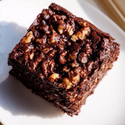 Warm Chocolate Fudge Brownies with Walnuts sit on a cooling rack, featuring melty chocolate chips and toasted nut pieces for extra texture.