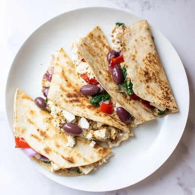 Golden tortilla folded around seasoned Greek chicken with olives peppers and spinach filling
