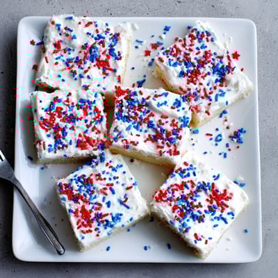 Baked patriotic 4th of July sugar cookie bars spread with vanilla frosting and decorated for Independence Day