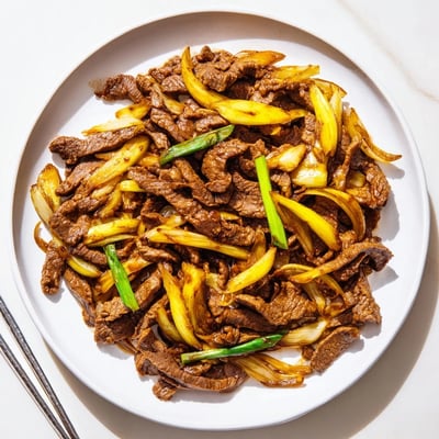 Savory Chinese stir fry featuring caramelized onions and tender crispy beef in glossy sauce