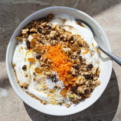 Wholesome carrot cake yogurt bowl layered with spiced Greek yogurt, crunchy granola, and shredded coconut.