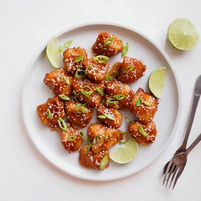 Juicy chicken thighs coated in glossy honey sriracha glaze with sesame seed garnish